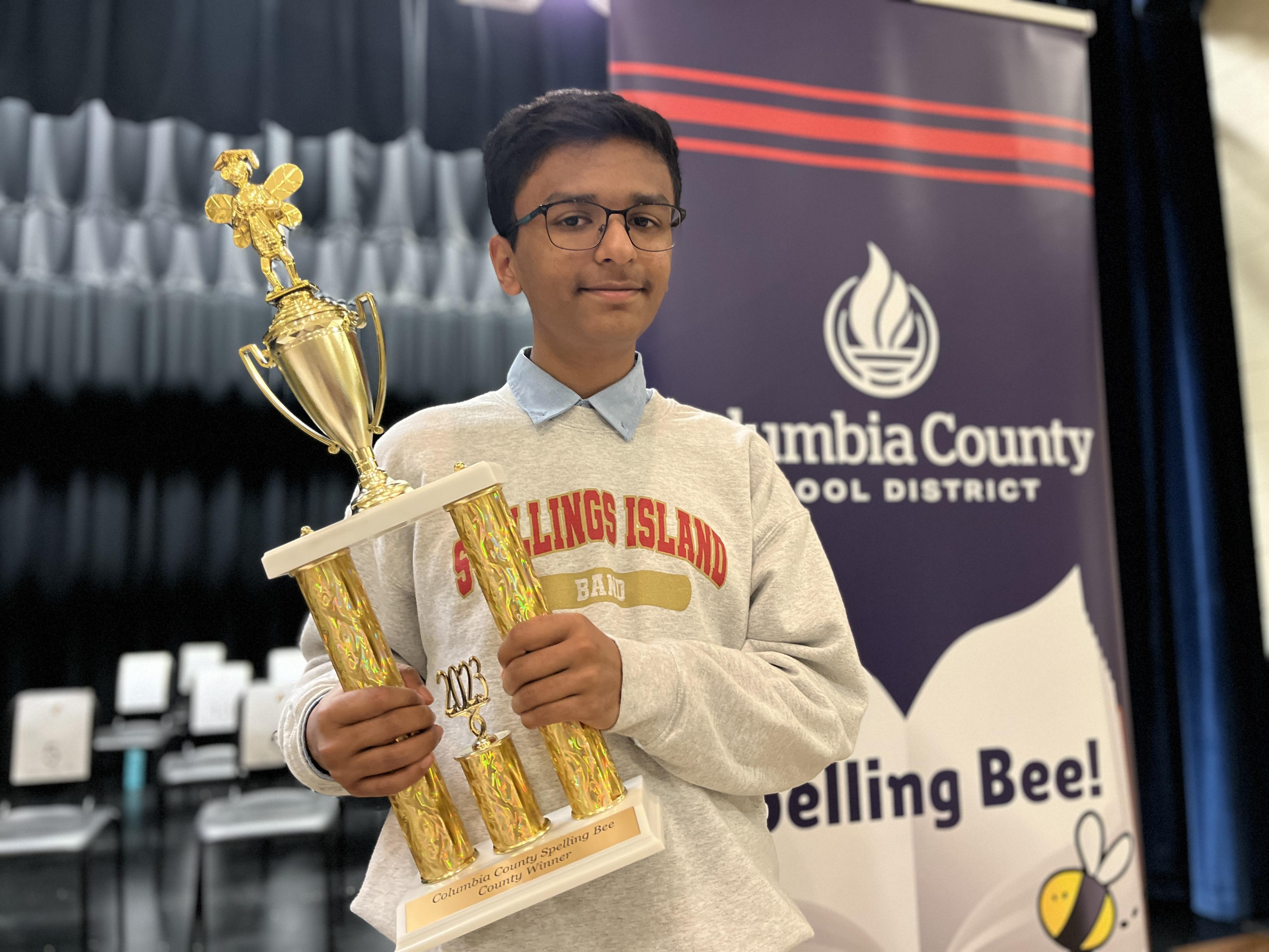 student smiling with trophy